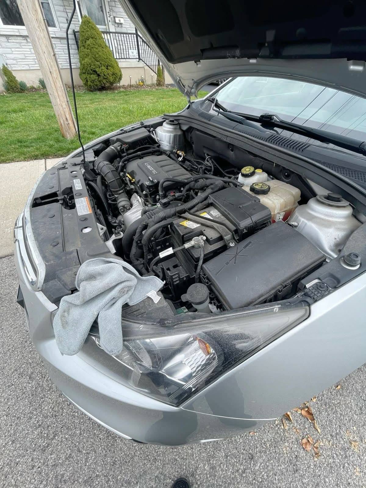 Silver vehicle with the hood open during a mobile diagnostics and engine bay inspection